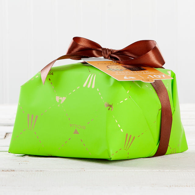 A green rectangular panettone with brown ribbon and decorative patterns, placed on a white surface.